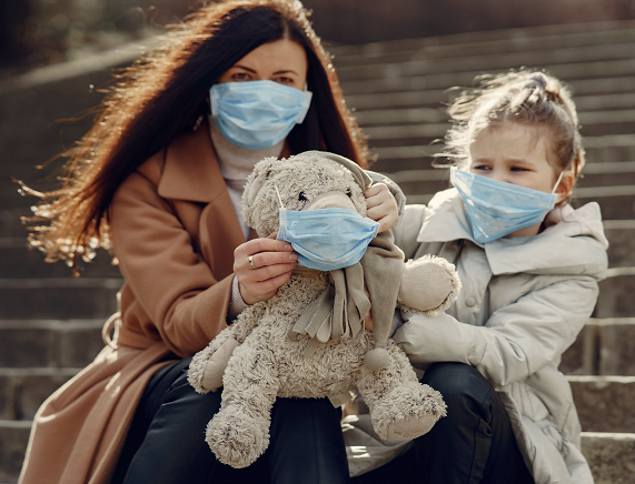 Kobieta i dziewczynka z misiem w maseczkach na twarzach