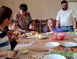 dzieci wraz z opiekunami przygotowują poczęstunek przy stole