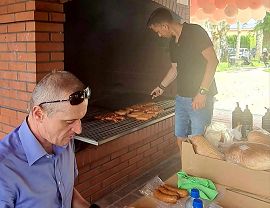 dwaj panowie przygotowują kiełbasę z grilla