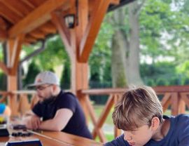 chłopcy z instruktorem w czasie nauki gry w warcaby