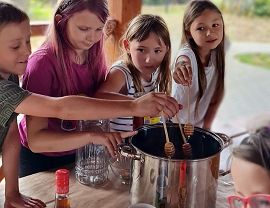dzieci nabierają miód ze srebrnego garnka
