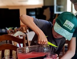 chłopiec nalewa lemoniadę z dzbanka do szklanki