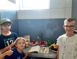 trzech chłopców  wkuchni w przegląda książkę kucharską