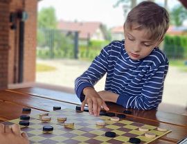 skupiony chłopiec wykonuje ruch pionem po planszy