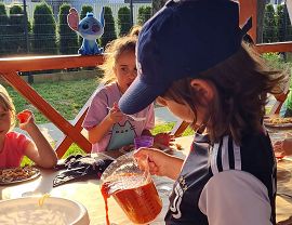 chłopiec w czapce z daszkiem polewa makaro sosem pomidorowym