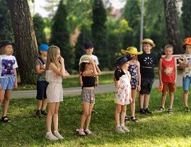 Dzieci na tle żywopłotu w czasie warsztatów teatralnych