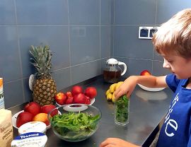 chłopiec przekłada liście szpinaku z miski do szklanki