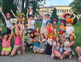 dzieci i opiekunowie pozują do zdjęcia w kolorowych kapeluszach scenicznych