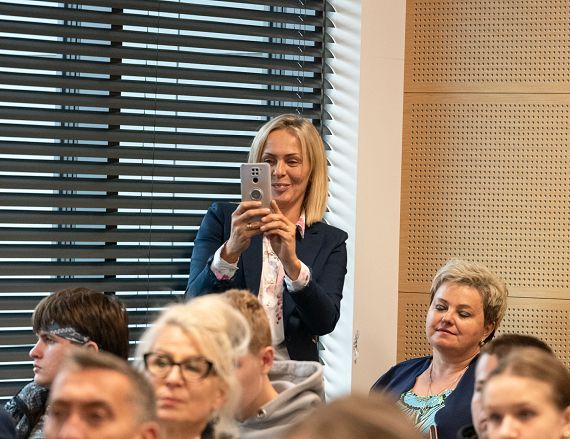 Zdjęcie przedstawia uczestników warsztatów, jedna osoba robi zdjęcie smartfonem.