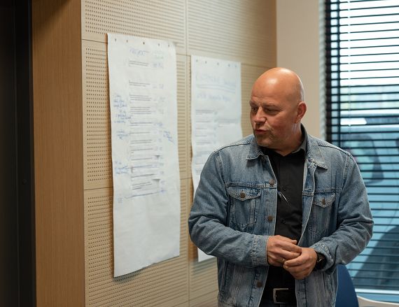 Zdjęcie przedstawia mężczyznę podczas prezentowania efektów pracy warsztatowej.