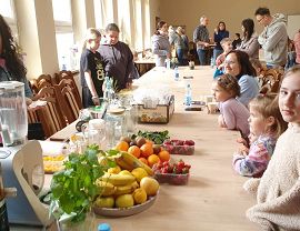 dzieci oczekujące na warsztaty kulinarne przy stole wypełnionym owocami