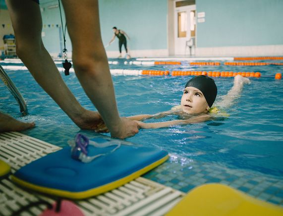 Freepik. trener uczy dziecko pływać